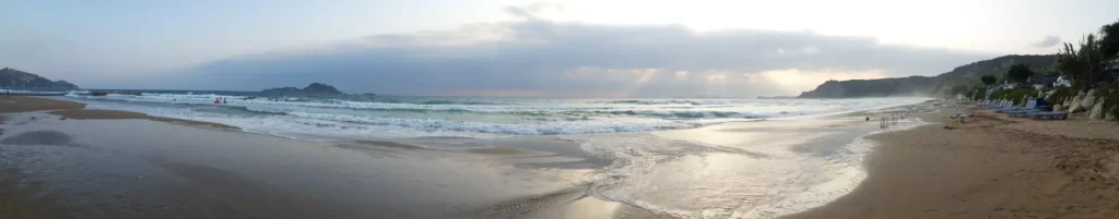 corfu arillas beach waves clouds and sun rays panoramic 2 1920w 1024x201